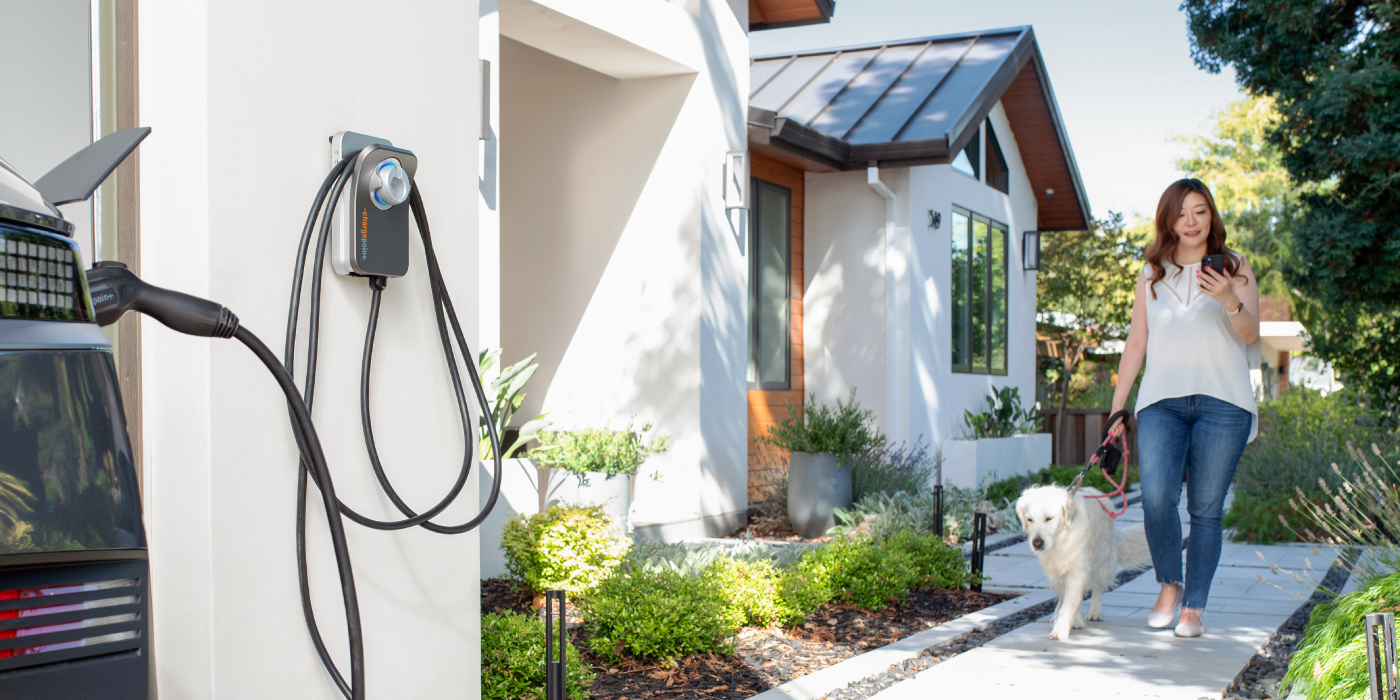 Person walking with a phone and a car getting charged by ChargePoint Home Flex